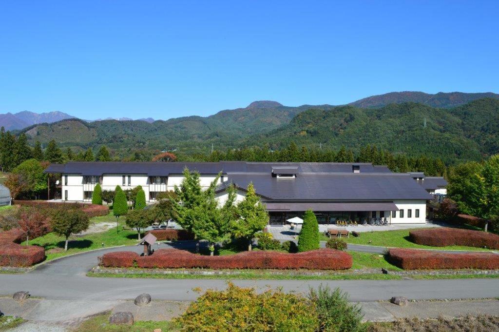 ein großes weißes Gebäude mit viel Landschaftsgärtnerei in der Unterkunft Hotel Familio Minakami in Minakami