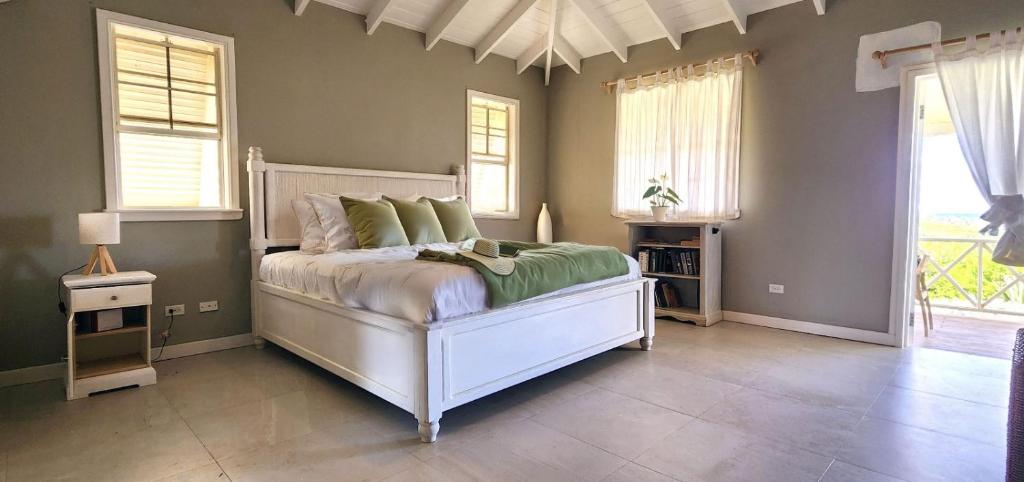 a bedroom with a bed with green and white pillows at Santosha Barbados in Saint Andrew
