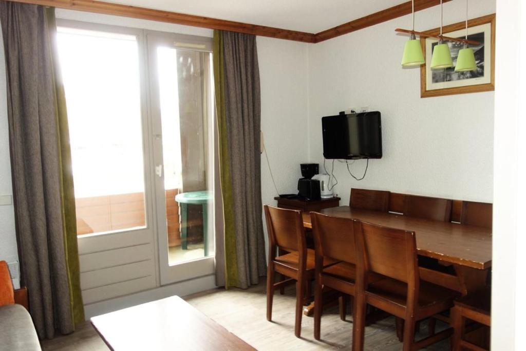une salle à manger avec une table, des chaises et une télévision dans l'établissement Résidence Bergers P&v - APPARTEMENT ALPE D'HUEZ QUARTIER BERGERS MAE-3061, à Huez