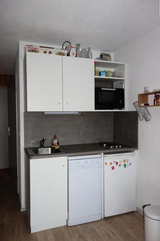 une cuisine avec des armoires blanches, un évier et un réfrigérateur dans l'établissement Résidence 4 Soleils - APPARTEMENT 2 PIECES + COIN MONTAGNE-ECLOSE EST MAE-3281, à Huez