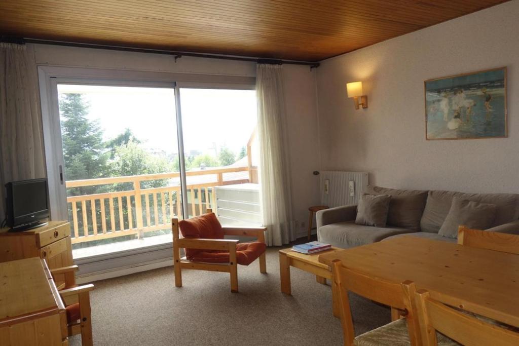 d'un salon avec un canapé et un balcon. dans l'établissement Résidence Azur - APPARTEMENT 2 PIECES + COIN MONTAGNE- ALPE D'HUEZ AVENUE DU RIF NEL MAE-3571, à Huez