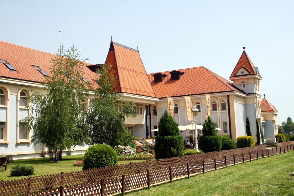 un bâtiment avec une clôture devant une cour dans l'établissement Hotel Prezident, à Palić
