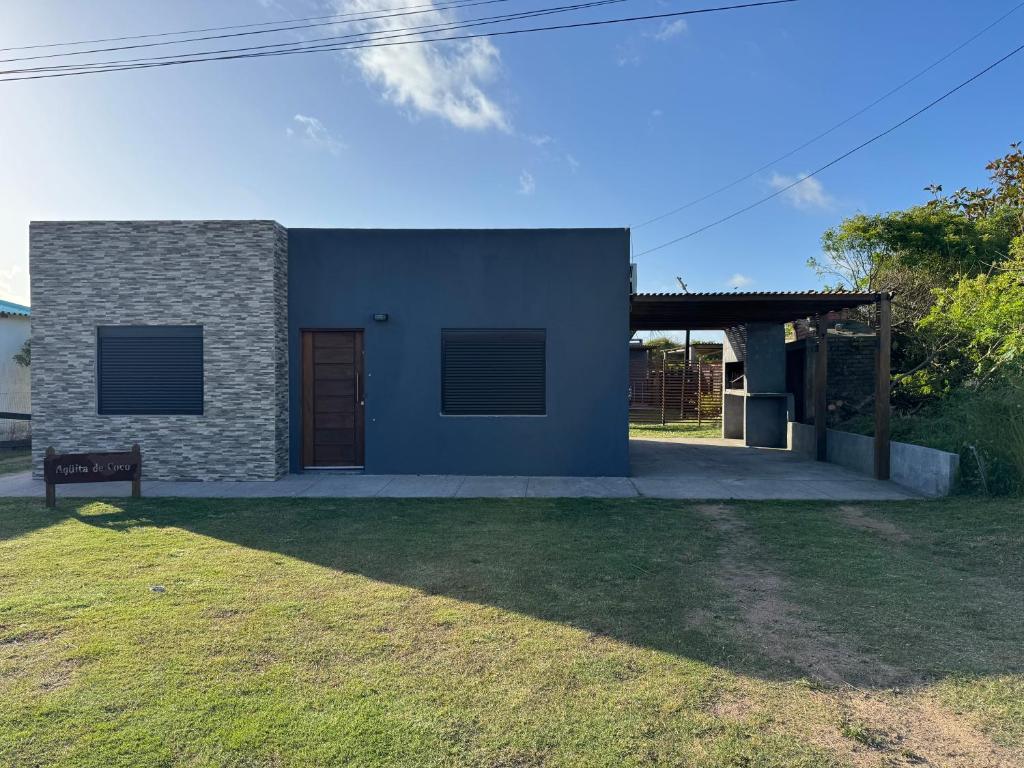 a blue house with a door and a grass yard at ᗷᖇᑌᗰᗩ in Barra del Chuy