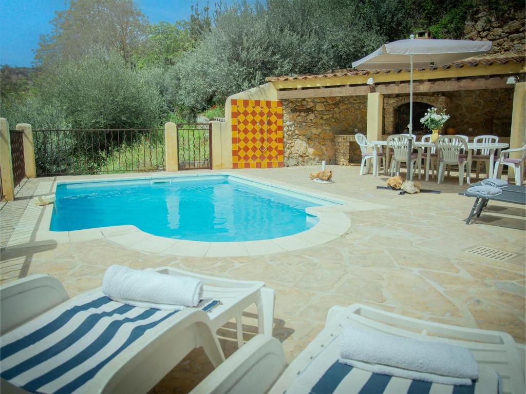 una piscina en un patio con sillas y mesa en Maison Jaune, en Cotignac