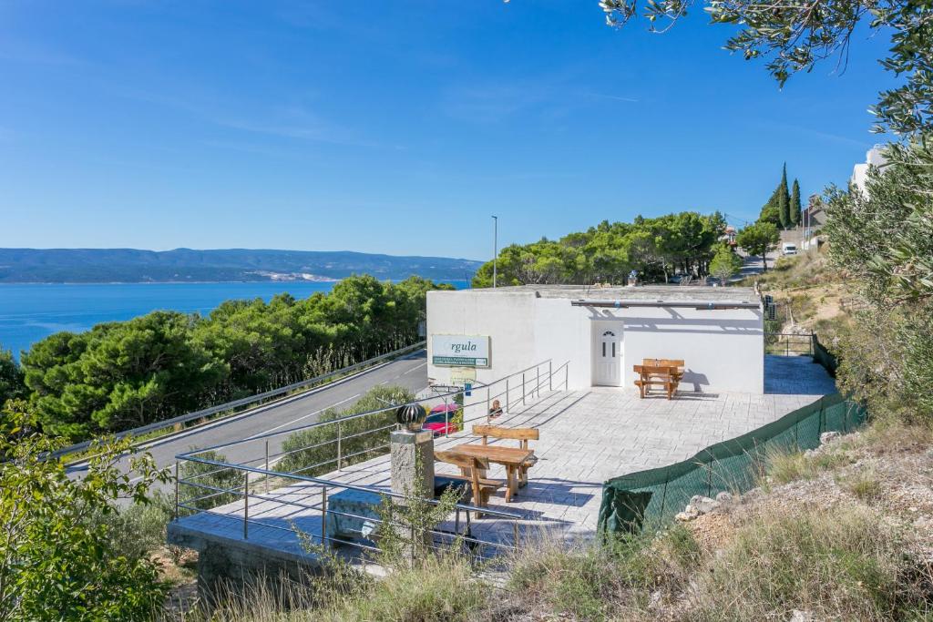a building with picnic tables on the side of a hill at Apartments with parking space Marusici, Omis - 954 in Mimice