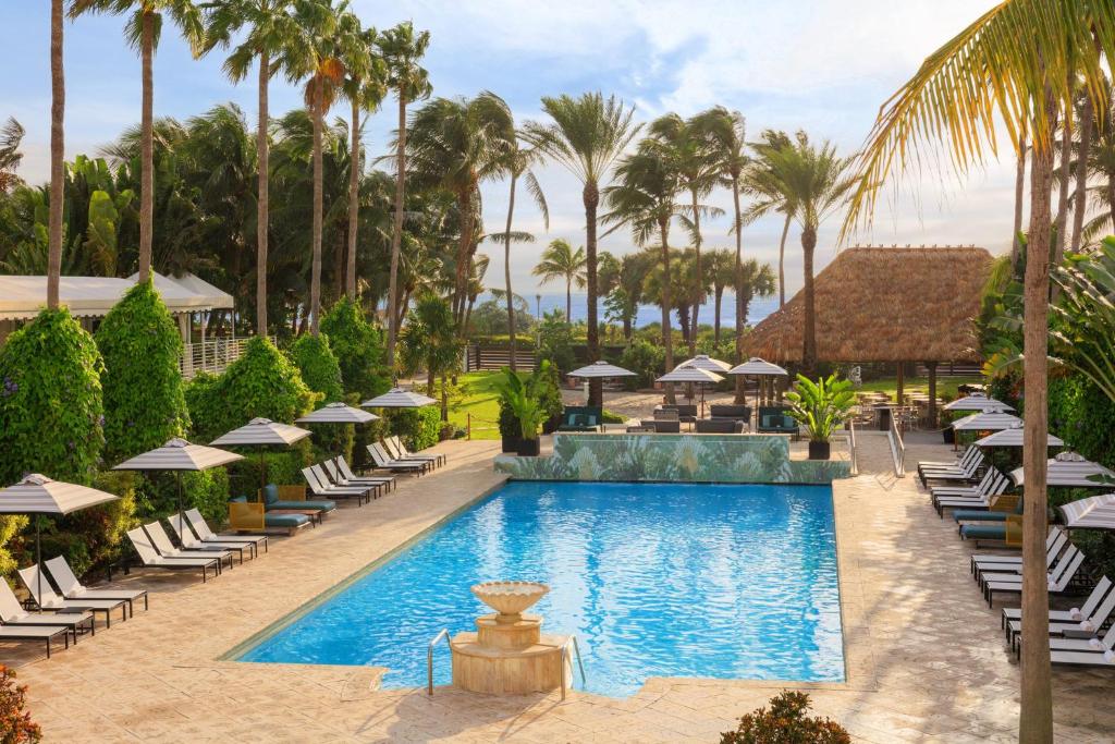a pool with lounge chairs and umbrellas at a resort at Kimpton Surfcomber Hotel by IHG in Miami Beach