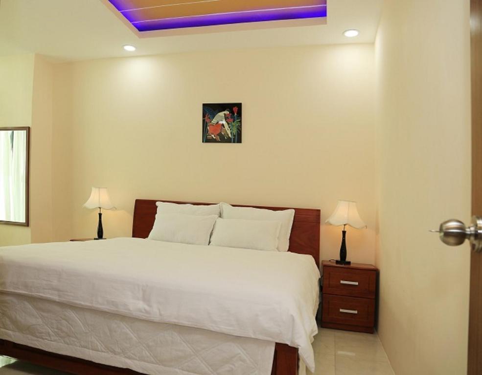 una camera con un grande letto bianco e due lampade di Nha Trang Apartment - Unit 3706 a Nha Trang