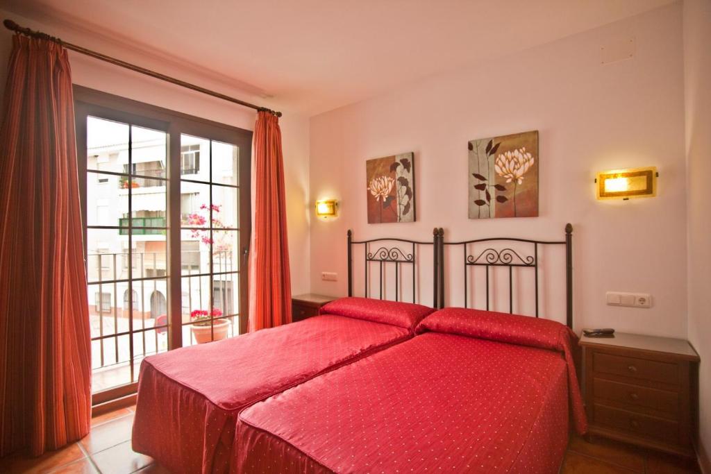 1 dormitorio con cama roja y ventana en Hostal Palomares, en Salobreña