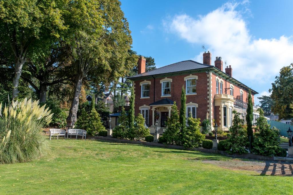 an old brick house with a lawn in front of it at Charades Guest House in Hereford