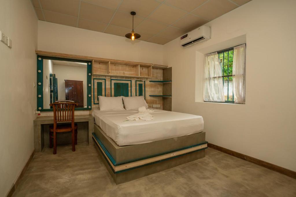a bedroom with a bed and a desk and a window at Ivy Cottage in Ahangama
