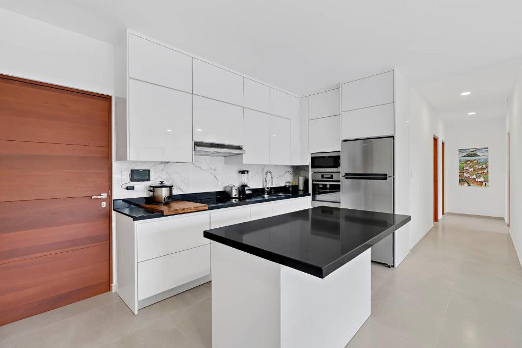 una cucina con mobili bianchi e un piano di lavoro nero di Casa Corales Dreams Deluxe a Playa Flamingo