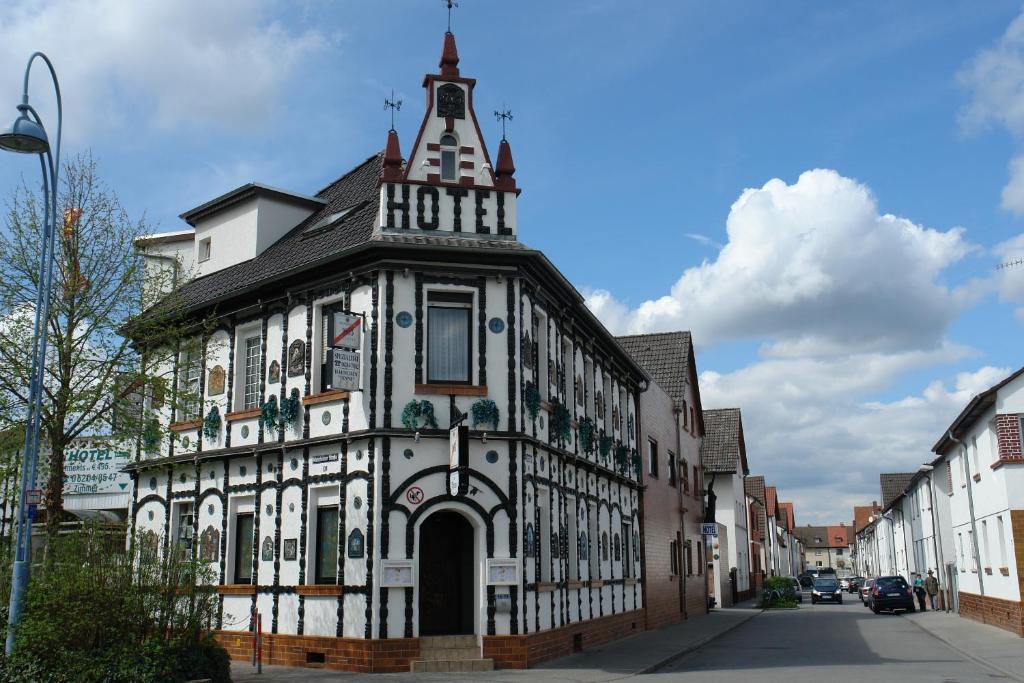 ein altes Gebäude mit einem Uhrturm auf einer Straße in der Unterkunft Hotel Tenne in Viernheim