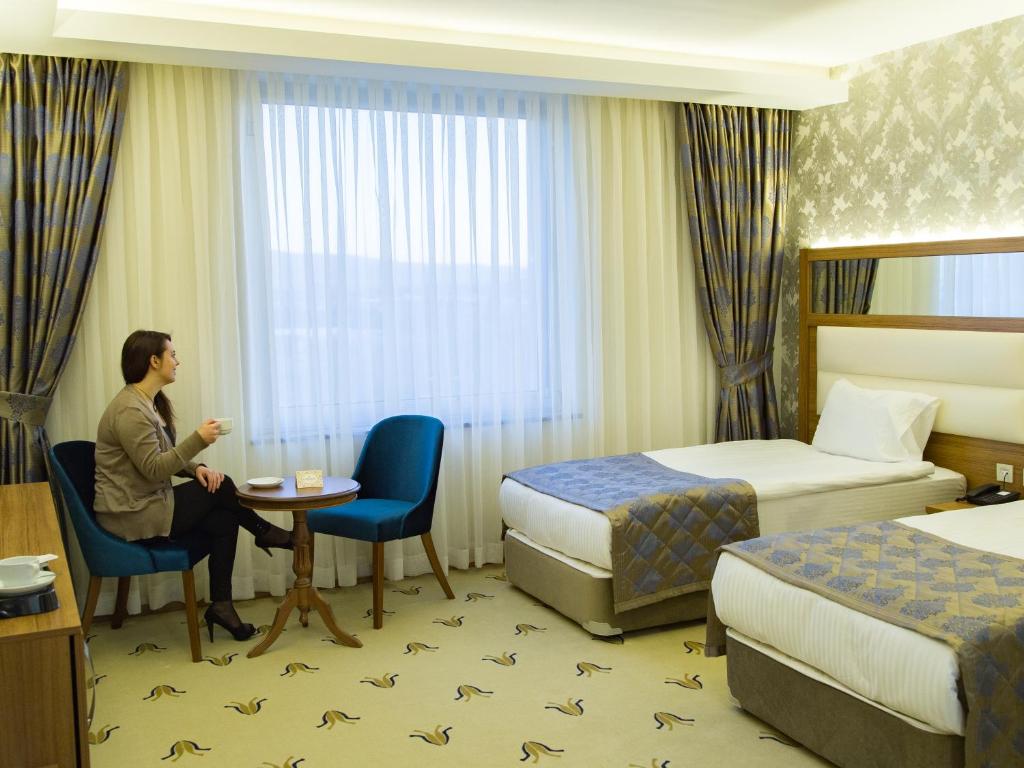 un homme assis à une table dans une chambre d'hôtel dans l'établissement Carmine Otel, à Kırıkkale
