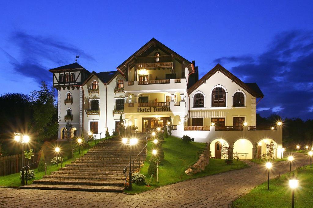 ein großes weißes Haus mit Lichtern an den Stufen in der Unterkunft Hotel Turnul in Moieciu de Jos