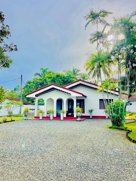 a white house with palm trees in front of it at Beach Star Villa Beruwala in Beruwala