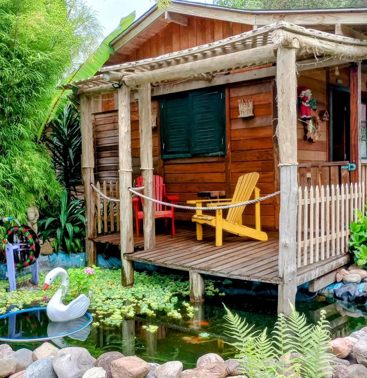 a wooden cabin with a pond in front of it at Chalé Cafofo in Campo Alegre