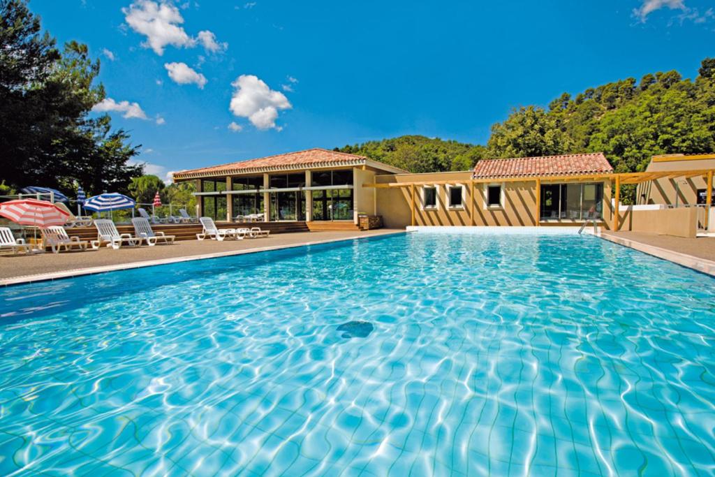 a large swimming pool in a tropical setting at Club Vacances Bleues Domaine de Château Laval in Gréoux-les-Bains