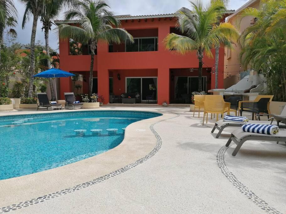 a swimming pool in front of a building with palm trees at 5 BD Luxury Villa with Large Pool & Minutes from Beach in Puerto Aventuras