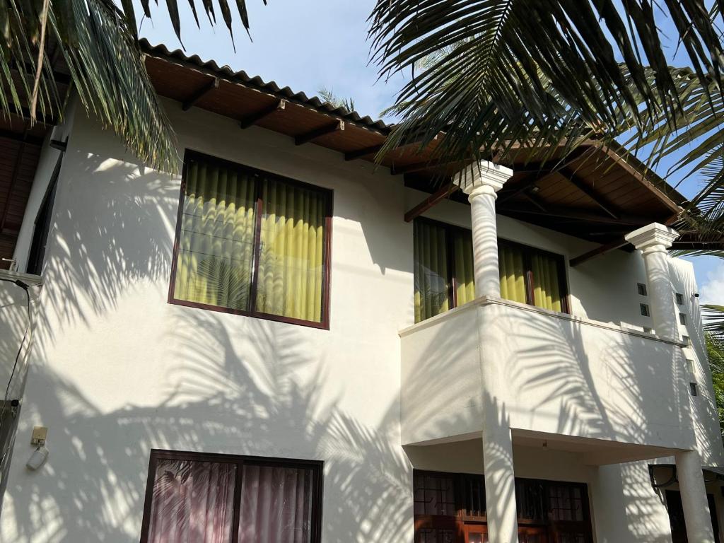 a white house with a palm tree in front of it at Villa 133 - 2 bed rooms in Dodanduwa