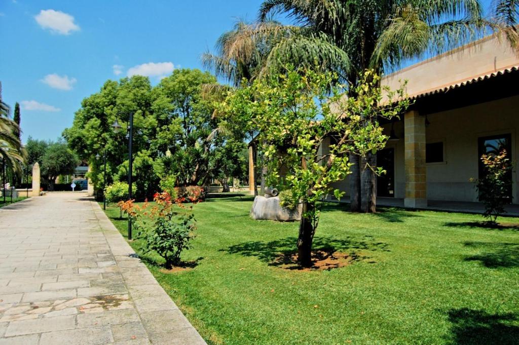 a green yard with trees next to a building at Antica Rudiae ricevimenti in Lequile