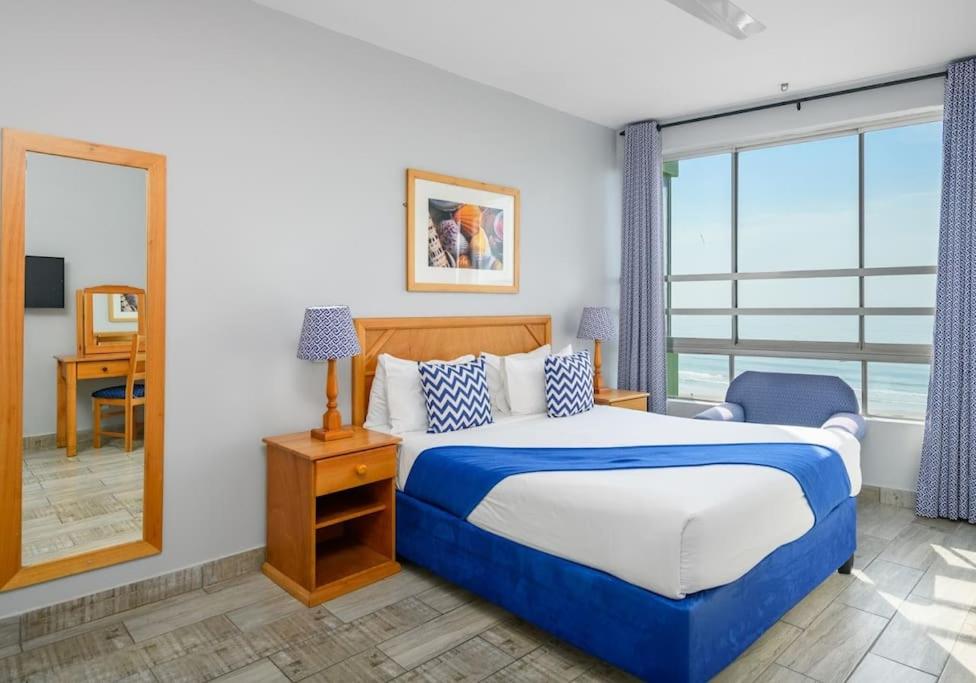 a bedroom with a bed and a desk and a mirror at Shaka Shores 7E in Durban
