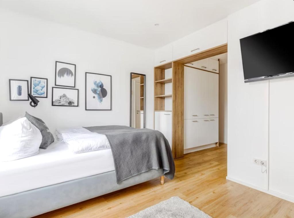 a white bedroom with a bed and a flat screen tv at My Suite II - Augsburg City - Netflix in Augsburg