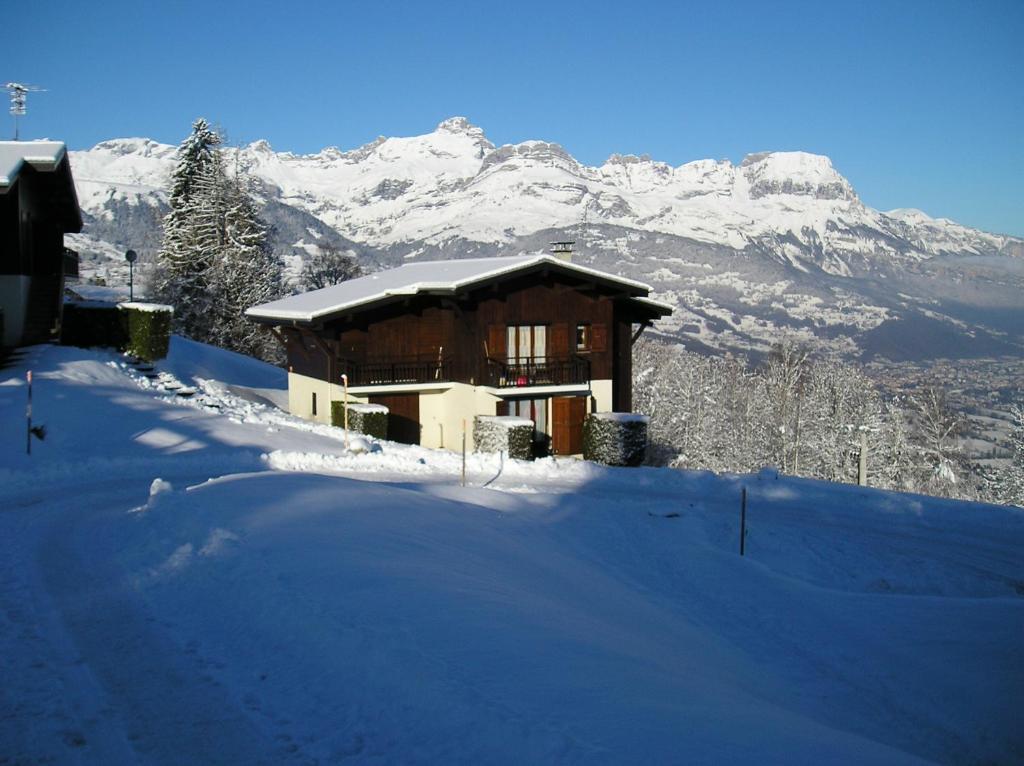 une maison dans la neige avec des montagnes en arrière-plan dans l'établissement La Grange N° 27 - Bât. 6, à Combloux