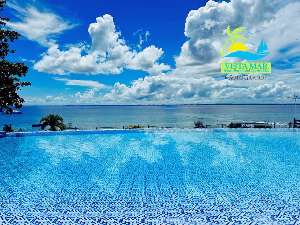 a swimming pool with the ocean in the background at Vista Mar Beach Resort and Country Club in Mactan
