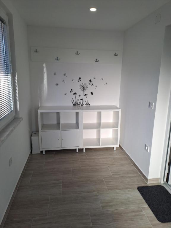 um quarto com uma prateleira branca com flores e borboletas na parede em Apartma Anci em Prosenjakovci