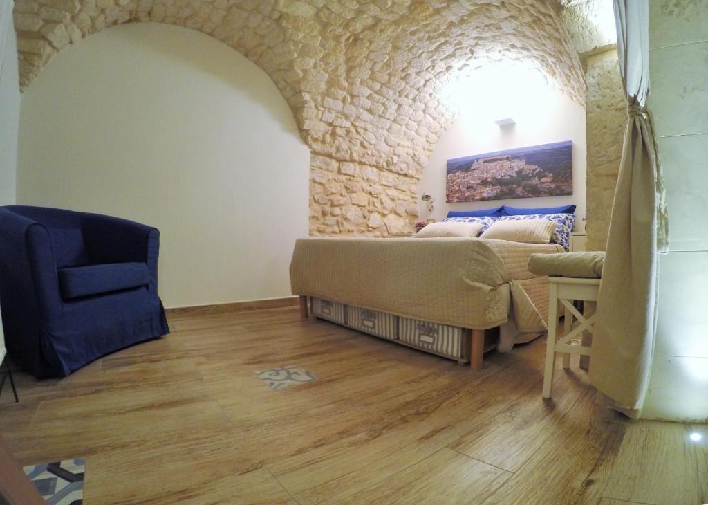 Pokój z łóżkiem, krzesłem i kamienną ścianą w obiekcie Al Borgo dell'Arte Suite w mieście Scicli