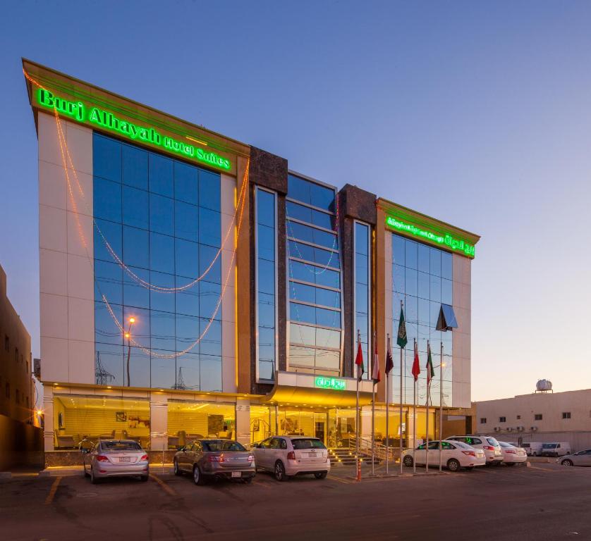 a large building with cars parked in a parking lot at Burj Alhayah Hotel Suites Alfalah in Riyadh