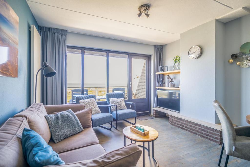 a living room with a couch and chairs and a tv at Appartementencomplex Juliana 156 in De Koog