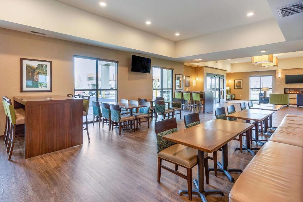ein Restaurant mit Holztischen, Stühlen und Fenstern in der Unterkunft Comfort Suites Burlington near I-5 in Burlington