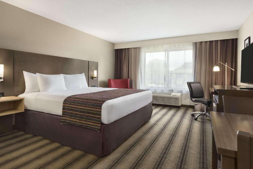 a hotel room with a large bed and a television at Country Inn & Suites by Radisson, Springfield Southeast in Springfield