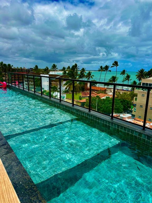 a swimming pool with a view of the ocean at Flats no centro de Porto de Galinhas próximo à praia opções com e sem piscina privativa in Porto De Galinhas