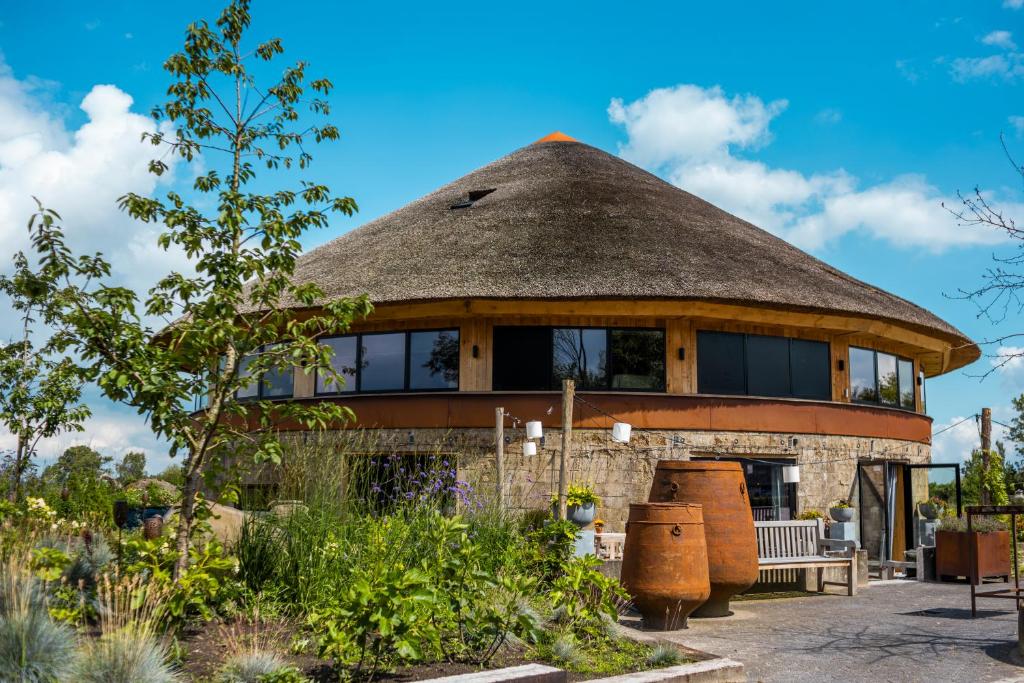 a round building with a thatched roof in a garden at De Perenhoeve in Ruinerwold