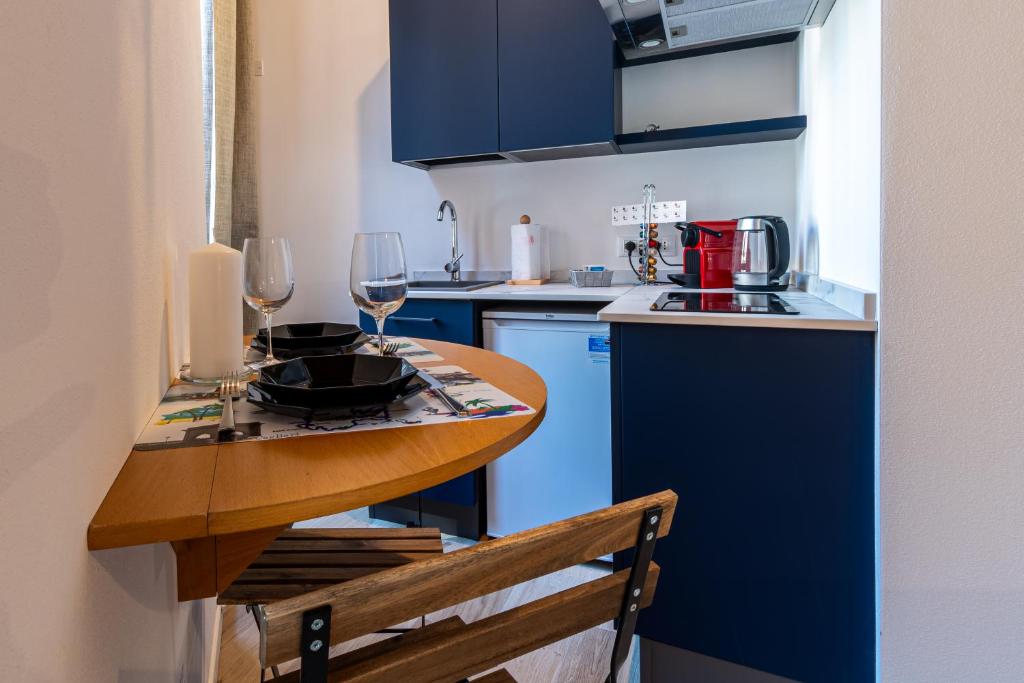 a kitchen with blue cabinets and a wooden table with wine glasses at Al Merlo da Diego in Cagliari