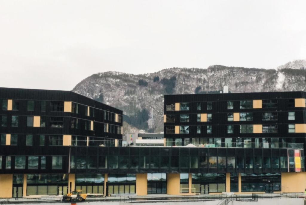 a large building with a mountain in the background at Toppleilighet på elvekanten med to romslige soverom in Førde