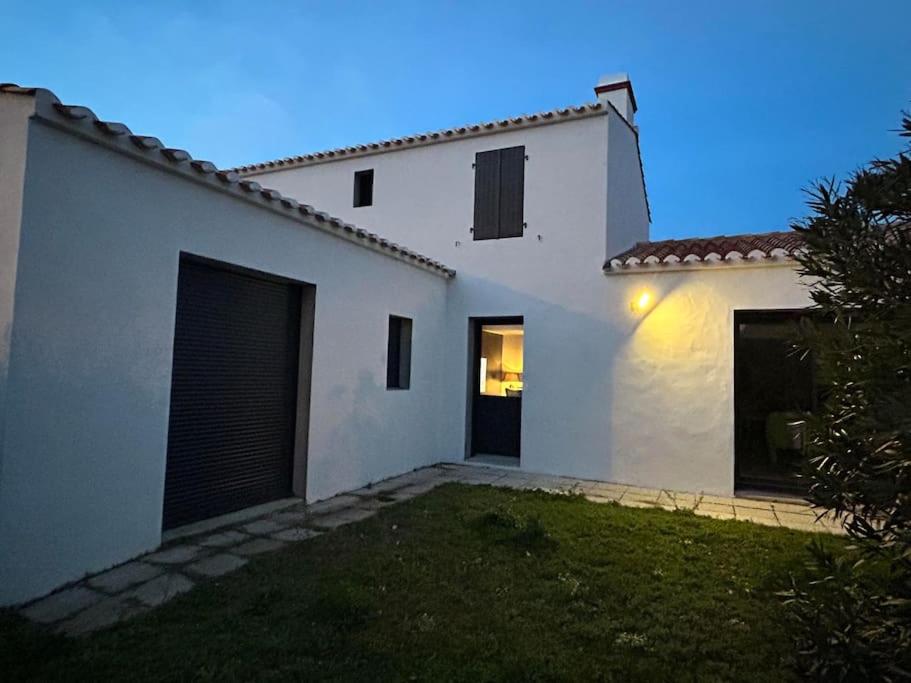 une maison blanche avec deux portes de garage dans une cour dans l'établissement L'Epine, à LʼÉpine