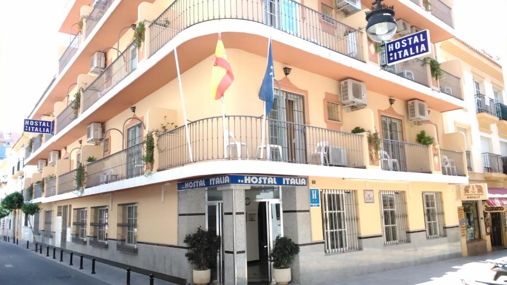 un edificio con dos banderas delante en Hostal Italia, en Fuengirola