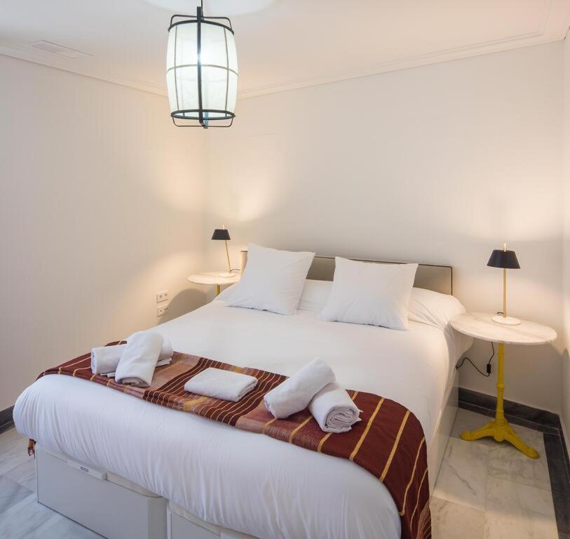 a bedroom with a large white bed with two tables at Chambre à louer in Saint-Étienne