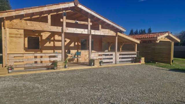 a large wooden cabin with a driveway in front of it at Chalet détente in Montaut