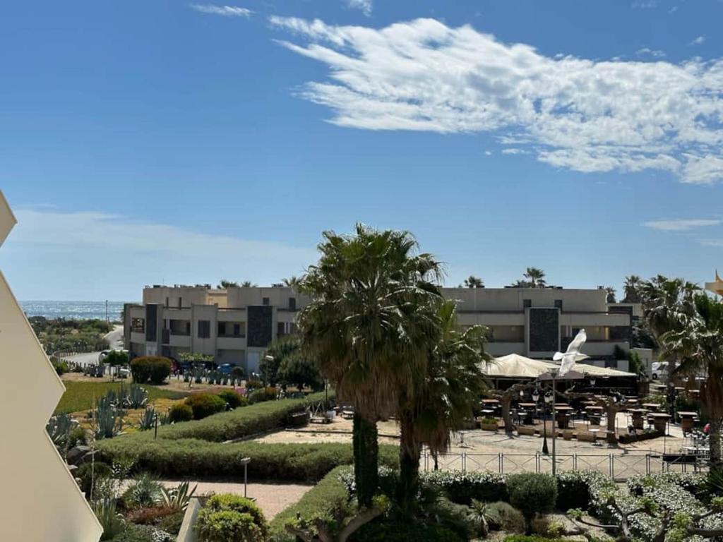 - une vue sur un complexe avec des palmiers et des bâtiments dans l'établissement Héliopolis J 201, au Cap d'Agde