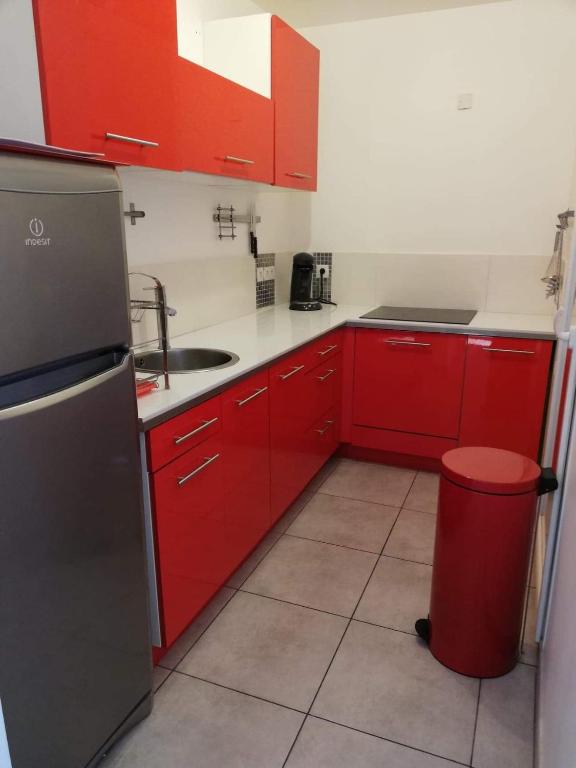 une cuisine avec des armoires rouges et une poubelle rouge dans l'établissement Studio calme proche de la gare de Borgo, à Borgo