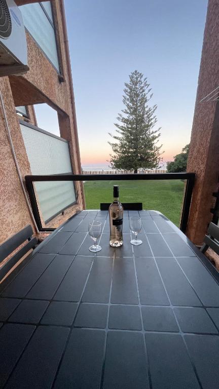 - une bouteille de vin assise sur une table avec 2 verres à vin dans l'établissement Chez Céline & Rudi, à Moriani-Plage