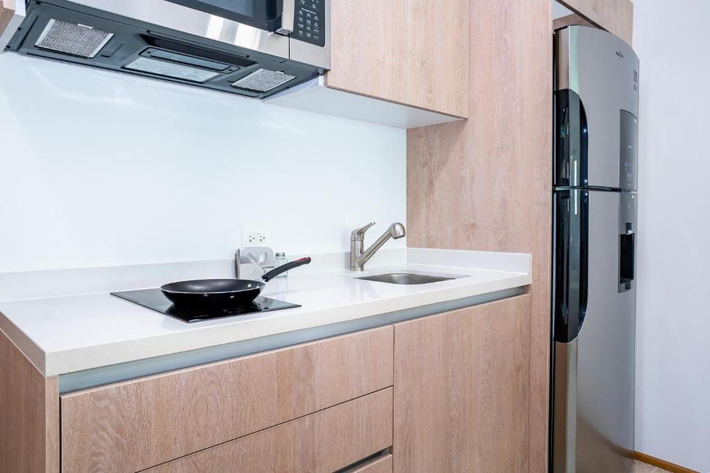 a kitchen with a sink and a refrigerator at Menesse Town Tower 202 condo in Playa del Carmen