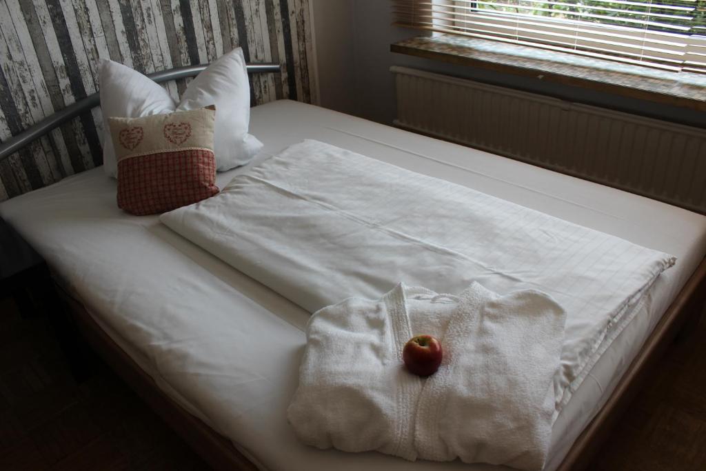 a bed with a white blanket and an apple on it at Gästehaus Lodge Fockbek in Fockbek