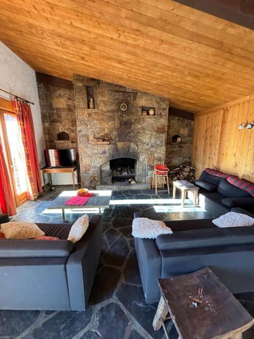 - un salon avec des canapés et une cheminée en pierre dans l'établissement Chalet de l'Ours - Pla d'Adet, à Cadeilhan-Trachère