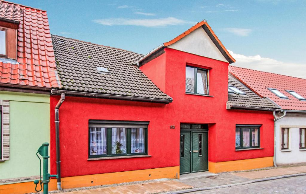 una casa rossa con una porta verde su una strada di Ferienwohnung Lassan - Wolgast a Lassan