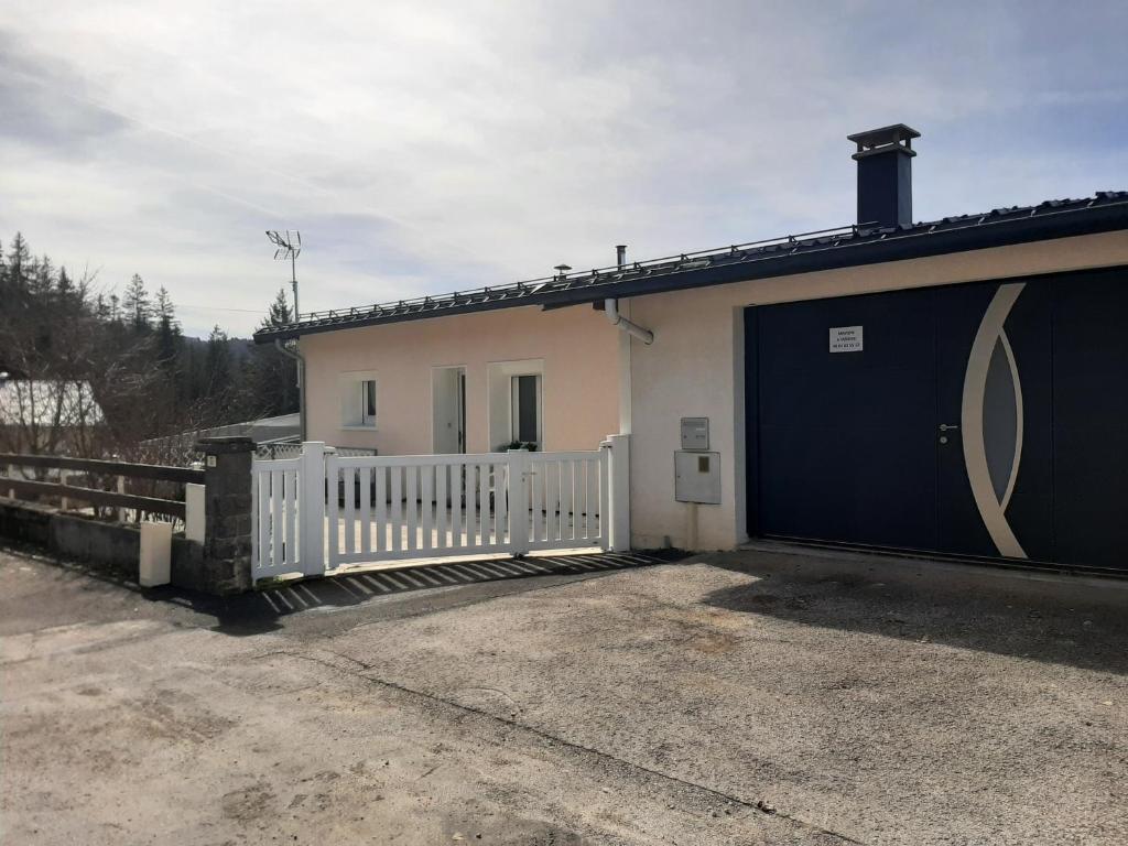 une maison blanche avec un portail et un garage dans l'établissement Maison de Vacances, à Morbier